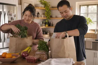 A couple unpacking groceries together in a kitchen.