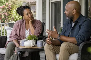 A couple talking over tea on a porch.