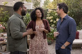 Three adults talk together during a small gathering on a leafy patio.